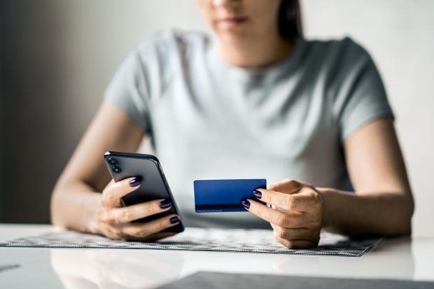 Frau mit Handy und Debitkarte