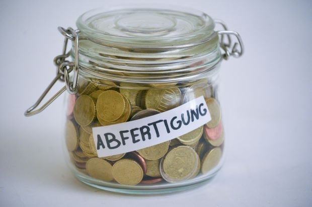 Glas mit Beschriftung "Abfertigung", gefüllt mit Münzen Glas mit Beschriftung "Abfertigung", gefüllt mit Münzen